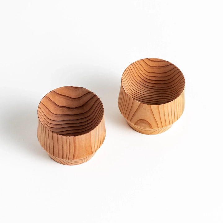 A pair of cedar wood sake cups featuring a distinctive ridged design, with natural wood grain details visible.