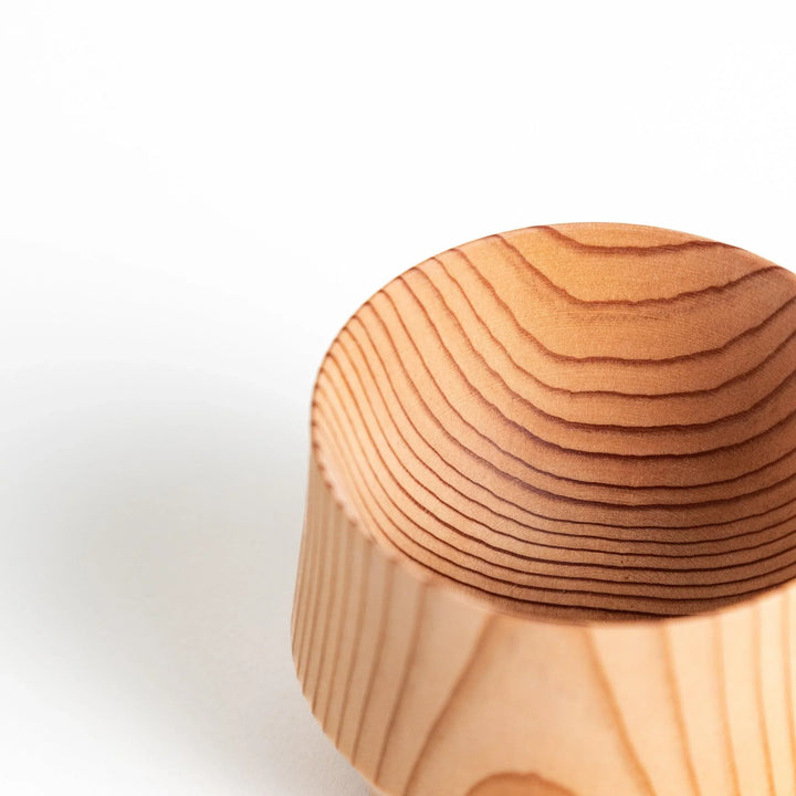 Close-up of a cedar sake cup, featuring a gently curved shape and distinct wood grain, emphasizing its artisan craftsmanship.