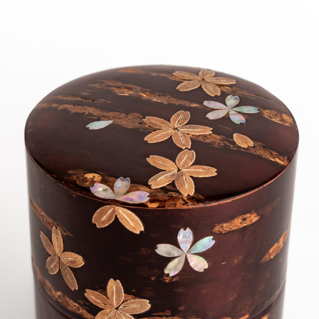 Elegant cherry bark tea caddy with mother-of-pearl cherry blossom inlay, perfect for storing and preserving fine tea leaves.