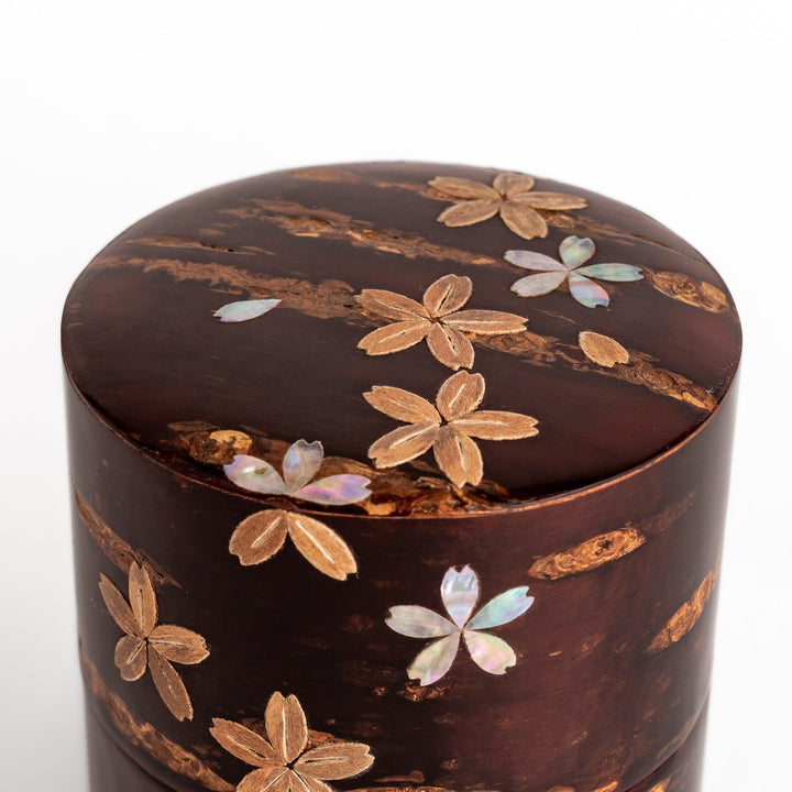 Elegant cherry bark tea caddy with mother-of-pearl cherry blossom inlay, perfect for storing and preserving fine tea leaves.