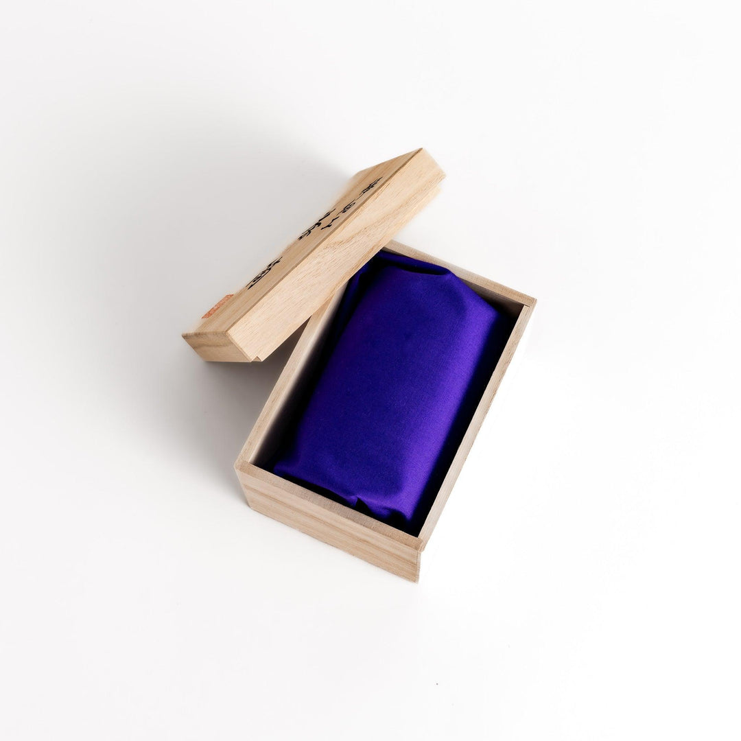 Open wooden box revealing a purple silk pouch, likely containing a delicate cherry bark tea caddy.