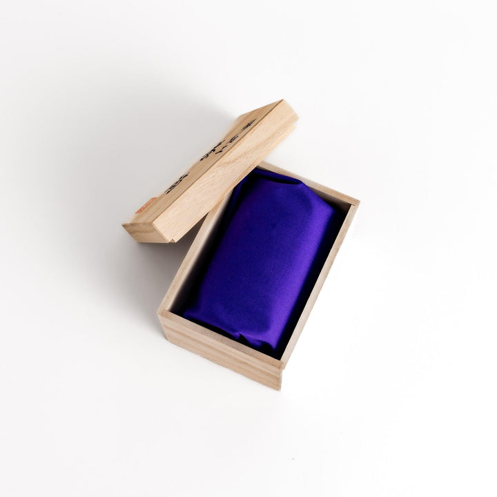 Open wooden box revealing a purple silk pouch, likely containing a delicate cherry bark tea caddy.