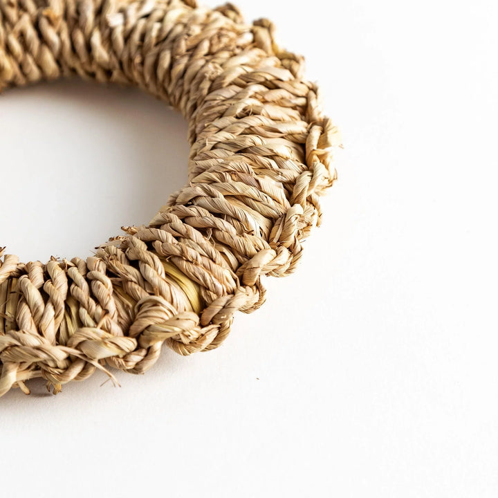 Close-up of an artisan rush trivet showing the intricate braided texture and a circular shape.