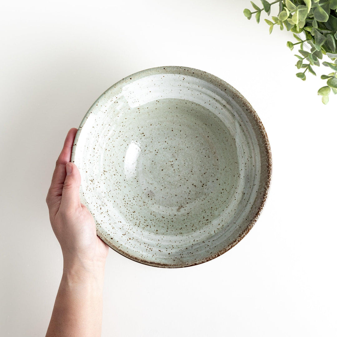 A light gray, wide-rimmed bowl with a textured and speckled surface.