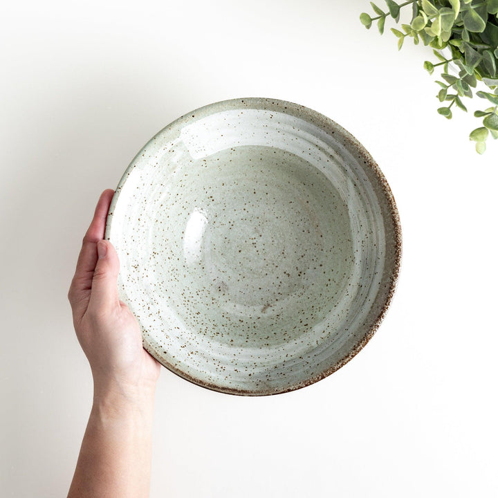 A light gray, wide-rimmed bowl with a textured and speckled surface.