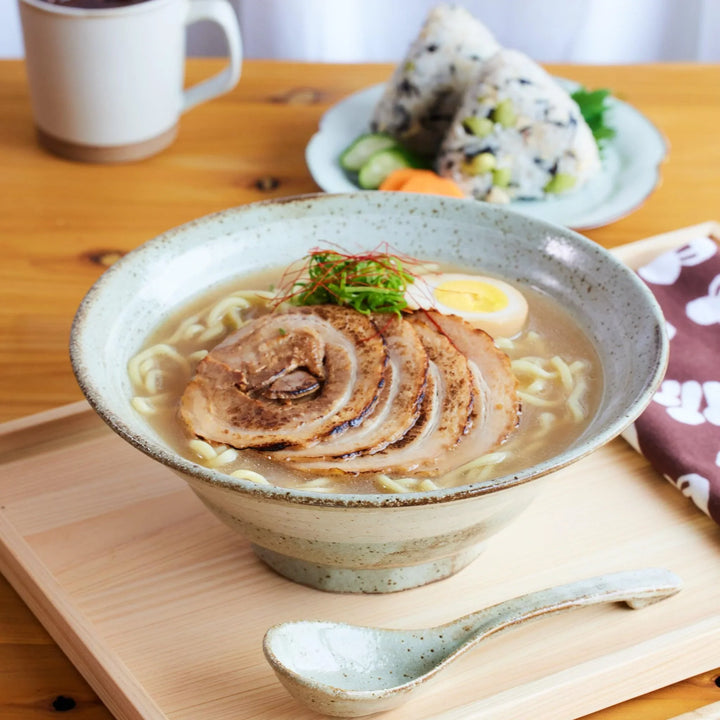 Ash glazed Japanese ramen bowl filled with ramen with matching ramen spoon.