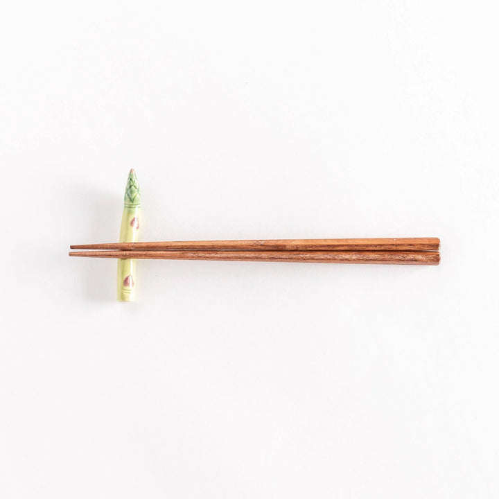 Ceramic asparagus chopsticks rest with chopsticks positioned across its surface.