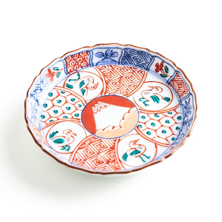 A vibrant ceramic dish with intricate patterns in blue, red, and green, centering around a depiction of Mount Fuji.
