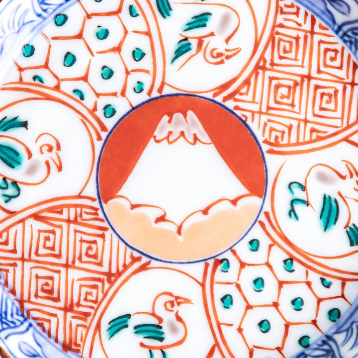 A vibrant ceramic dish with intricate patterns in blue, red, and green, centering around a depiction of Mount Fuji.