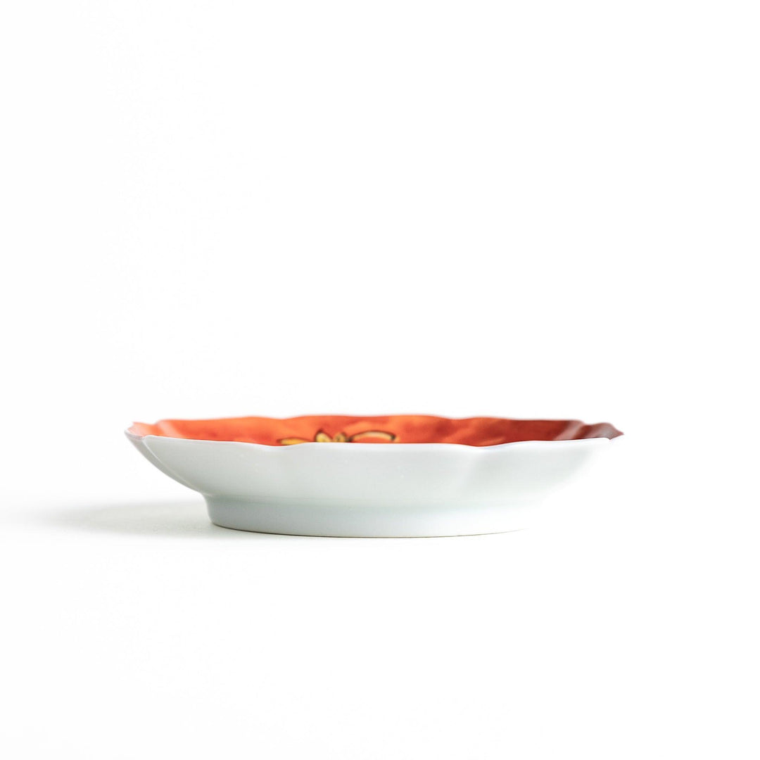 A white dish with a bright red border Mount Fuji, decorated with colorful maple leaves in red, yellow, and green.