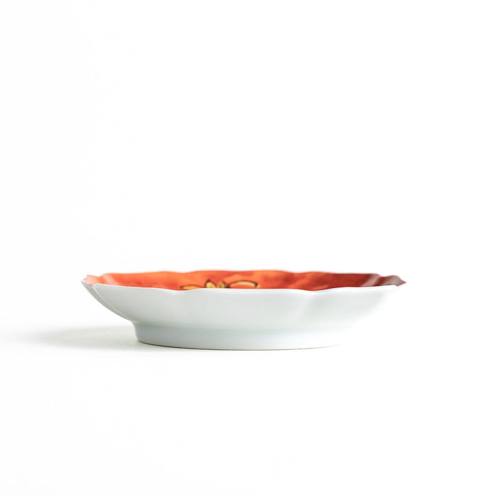 A white dish with a bright red border Mount Fuji, decorated with colorful maple leaves in red, yellow, and green.