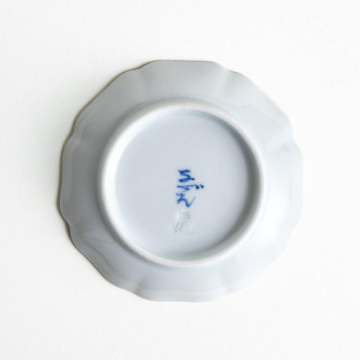 A white dish with a bright red border Mount Fuji, decorated with colorful maple leaves in red, yellow, and green.