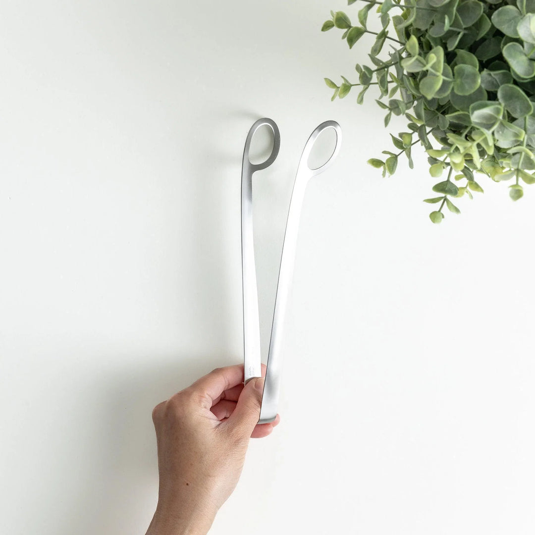 Curved stainless steel tongs with holes at the end for drainage