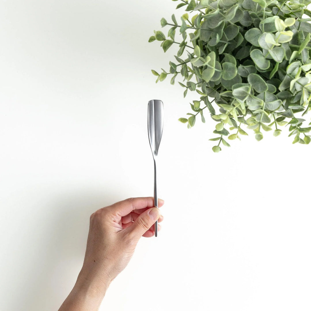 Long-handled stainless steel honey spoon with a uniquely shaped flat scoop