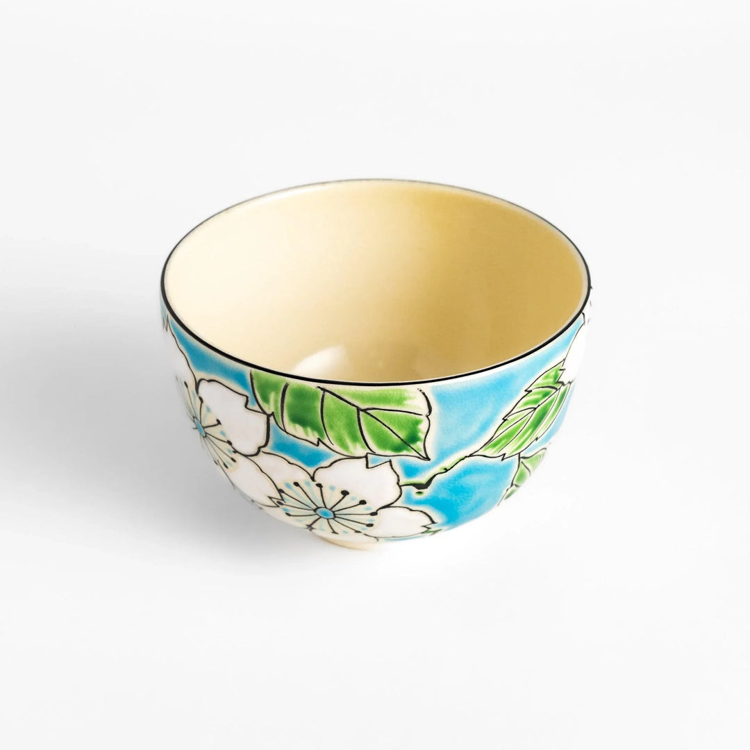 Plum Blossom Matcha Bowl with pink floral designs on a cream surface, adding elegance to your matcha moments.