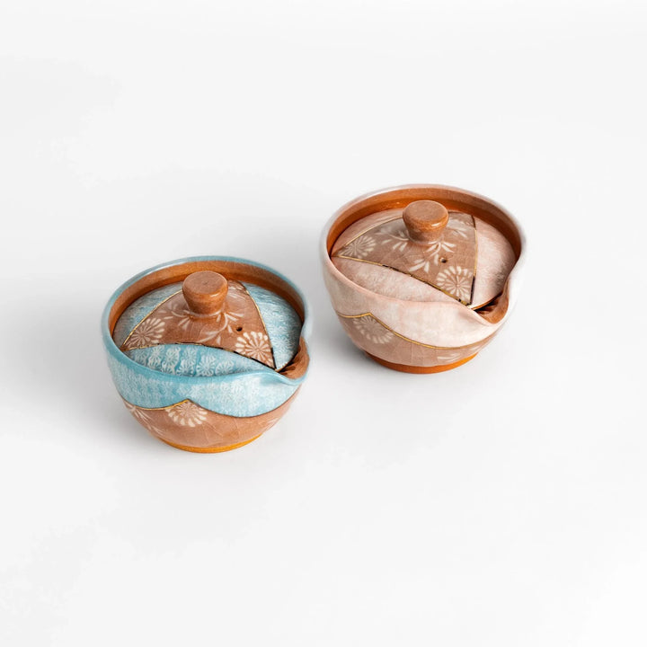 Two floral teapots in pink and blue with gold detailing and smooth spouts, perfect for elegant tea brewing.