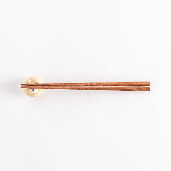 A wider view of the bear cupcake ceramic chopstick rest with chopsticks placed on it, highlighting its playful design.