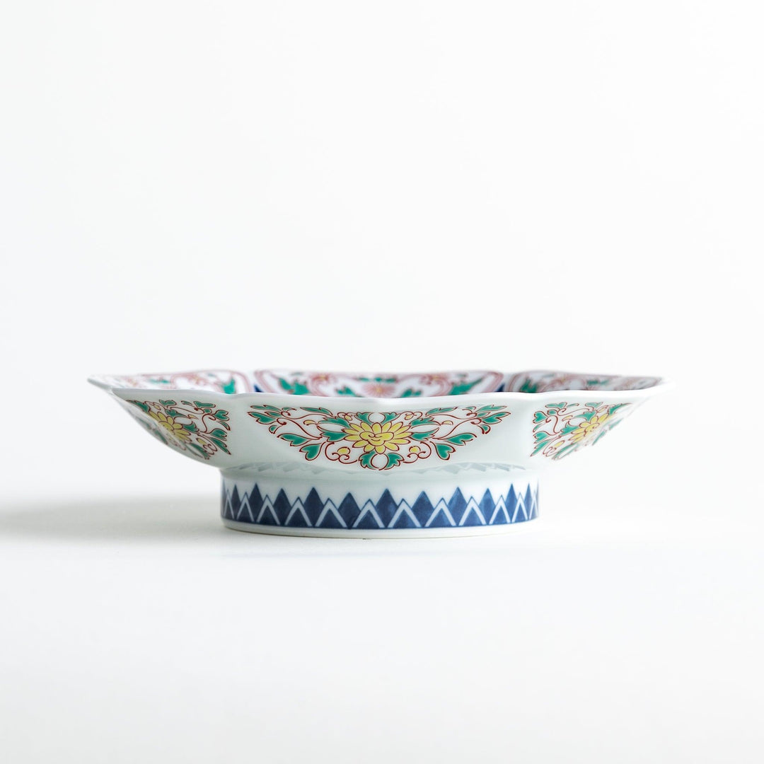 Blue dessert plate with geometric center and ornate floral rim in red green and gold with scalloped edge.