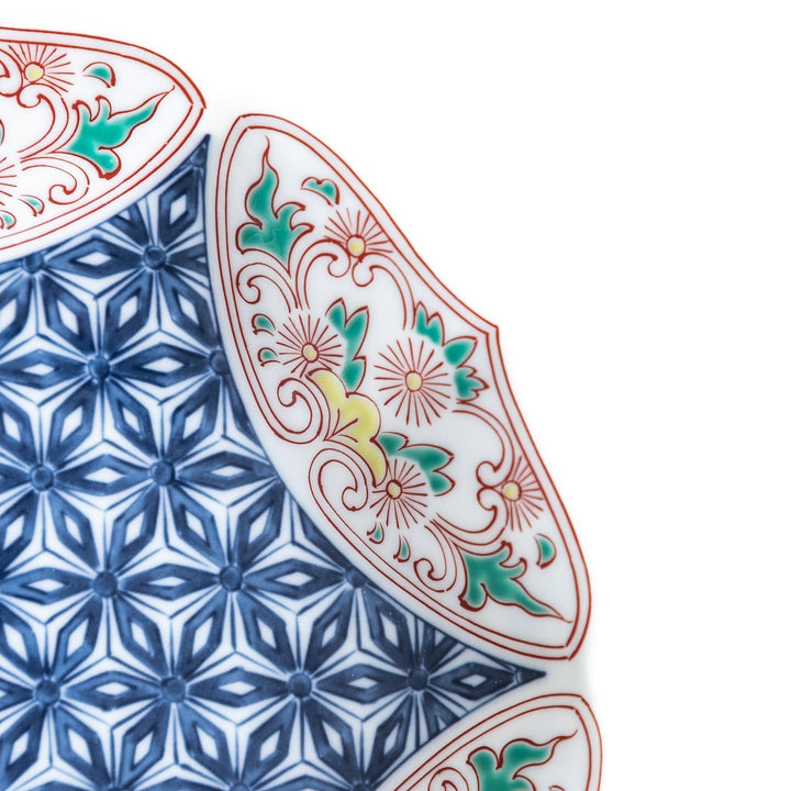 Blue dessert plate with geometric center and ornate floral rim in red green and gold with scalloped edge.