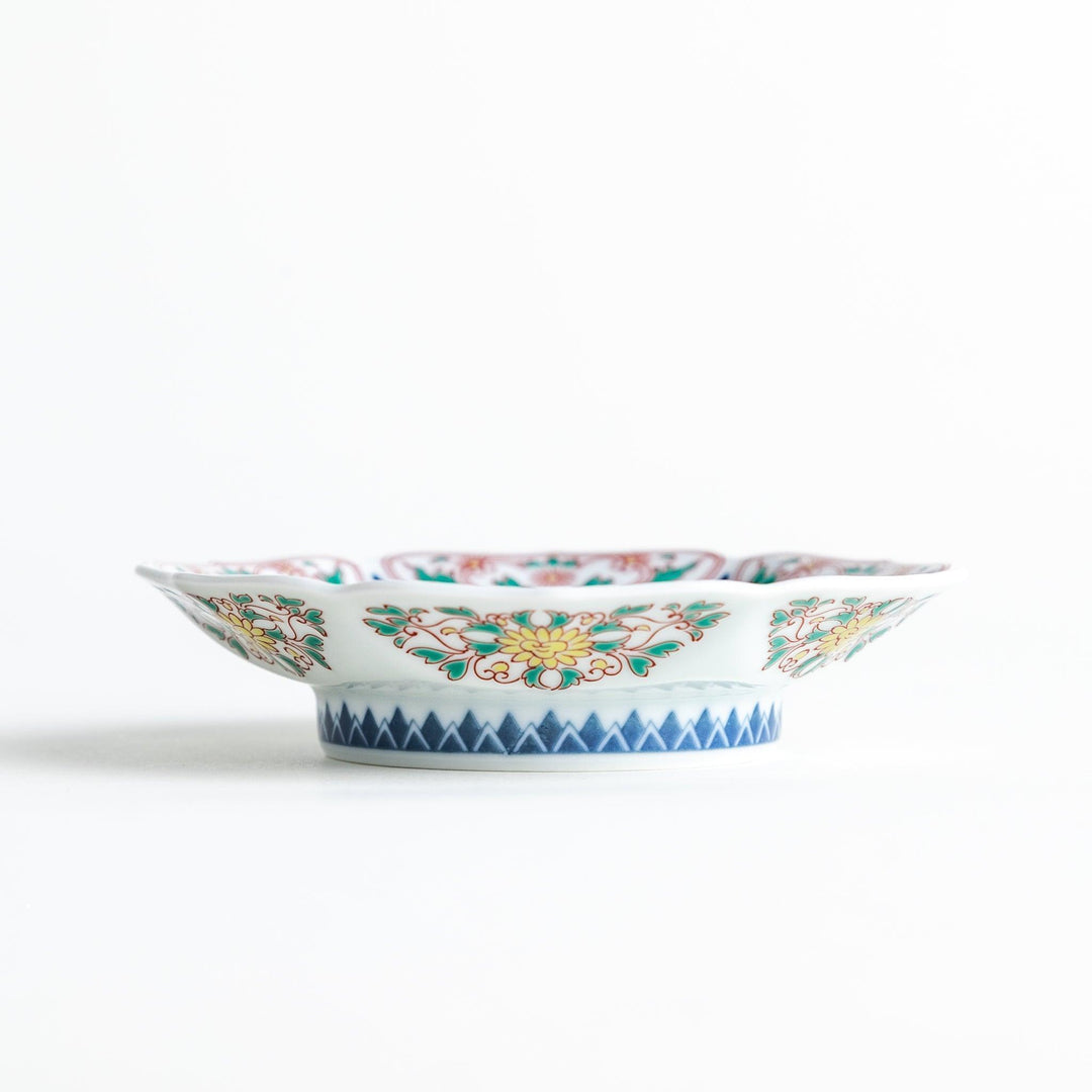 Sauce dish with blue geometric center and ornate floral rim in red green and gold with scalloped edge.