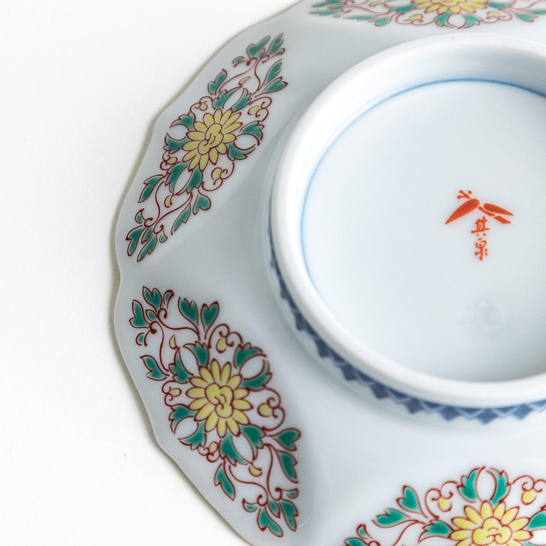 Sauce dish with blue geometric center and ornate floral rim in red green and gold with scalloped edge.