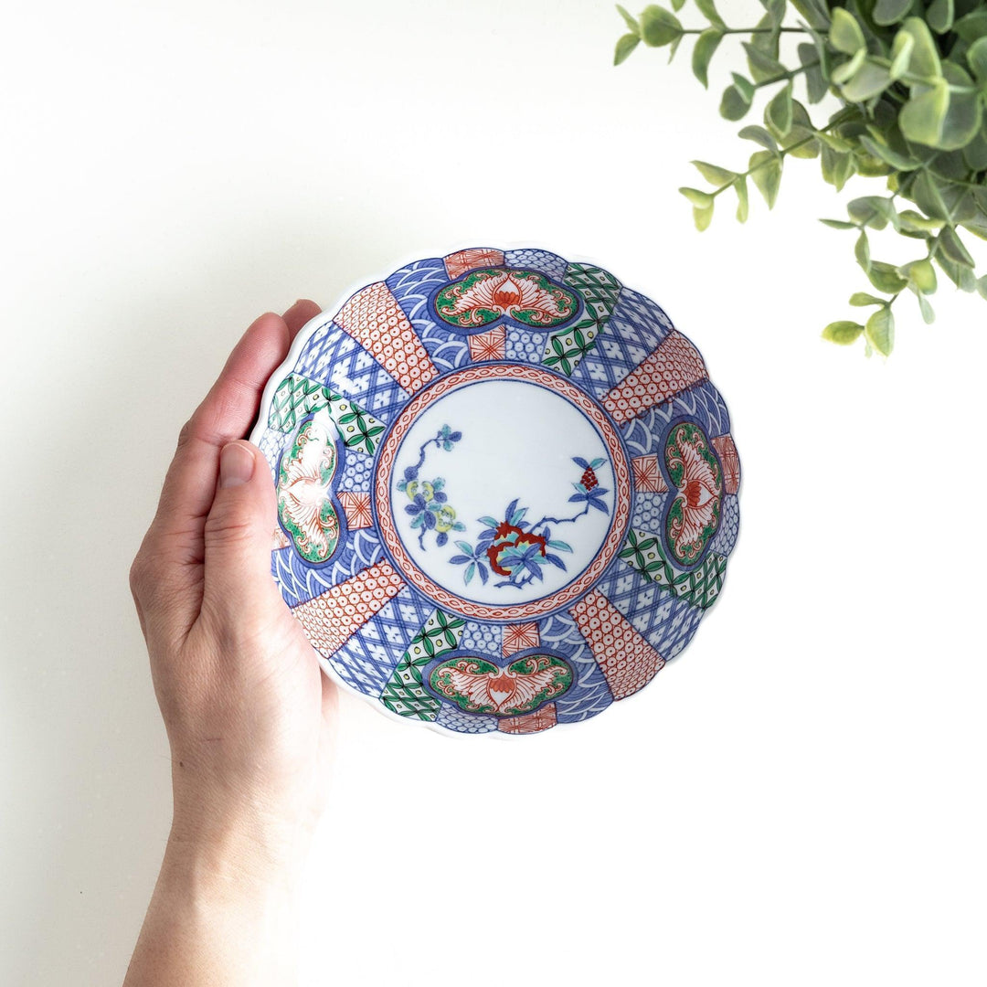 Round deep cereal bowl with scalloped rim floral center and blue red green patterns on white background.