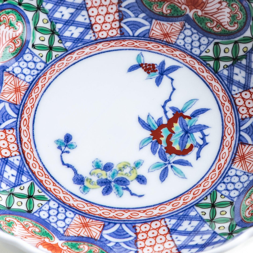 Round deep cereal bowl with scalloped rim floral center and blue red green patterns on white background.