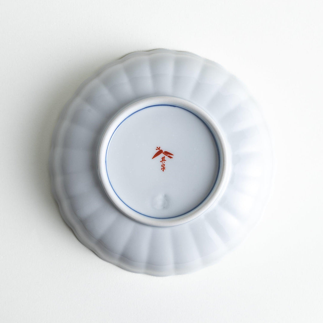 Round deep cereal bowl with scalloped rim floral center and blue red green patterns on white background.