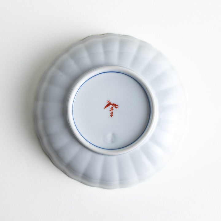 Round deep cereal bowl with scalloped rim floral center and blue red green patterns on white background.