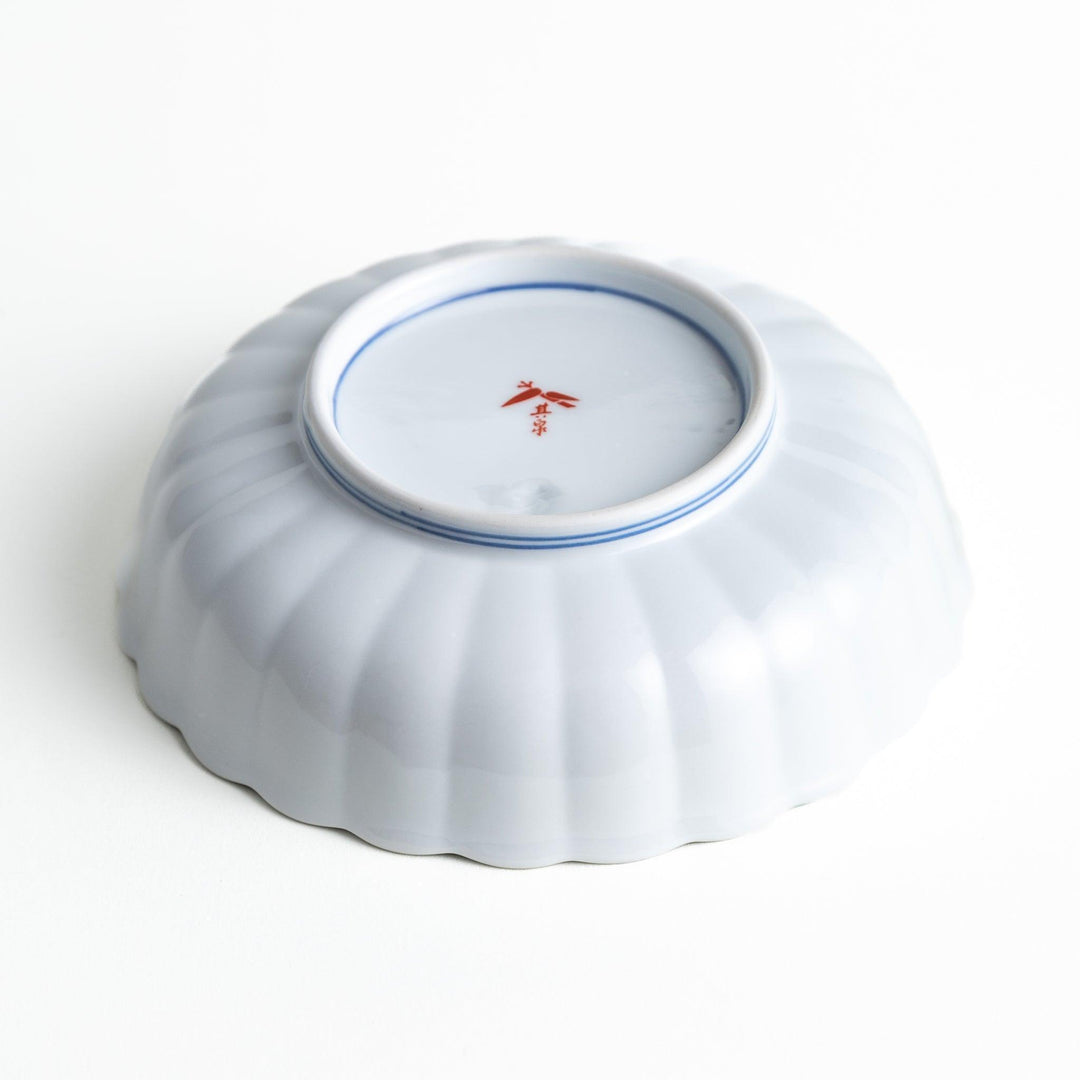 Round deep cereal bowl with scalloped rim floral center and blue red green patterns on white background.