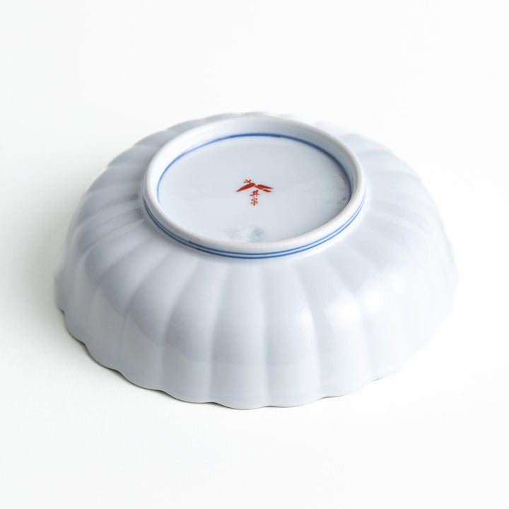 Round deep cereal bowl with scalloped rim floral center and blue red green patterns on white background.