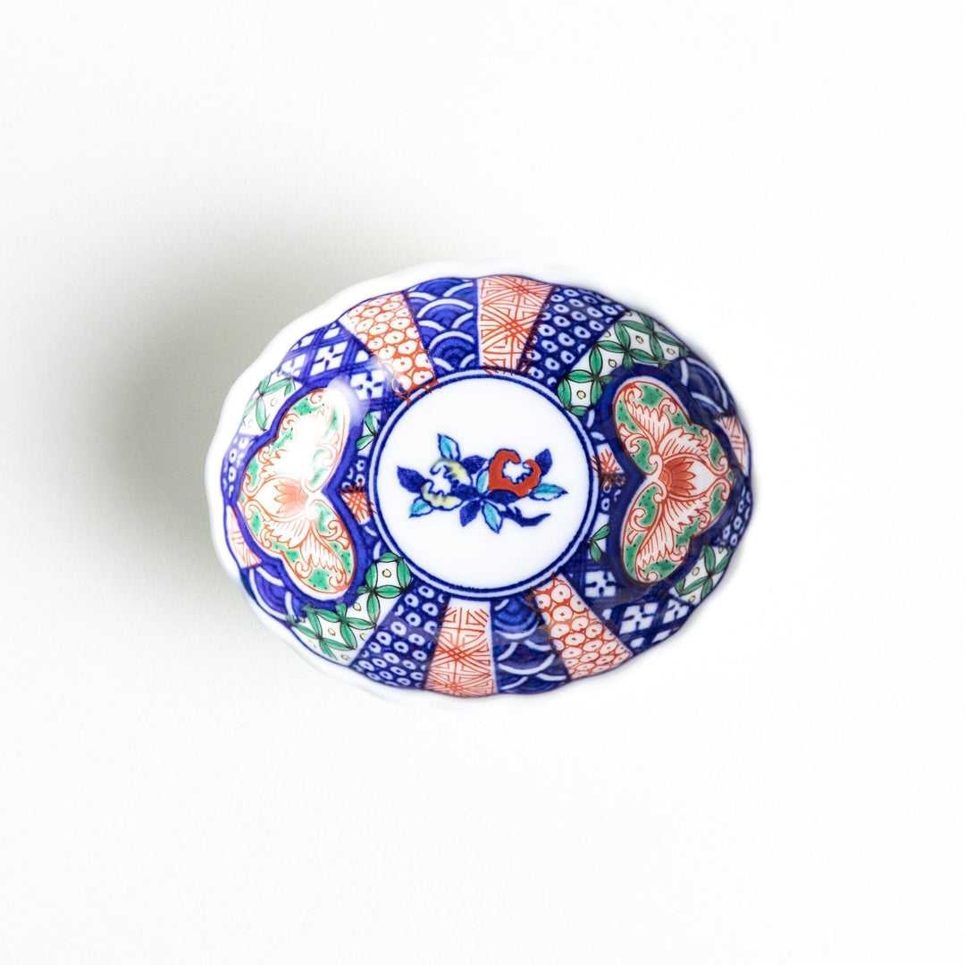 Small scalloped condiment bowl with floral motif and colorful geometric blue red and green patterns.