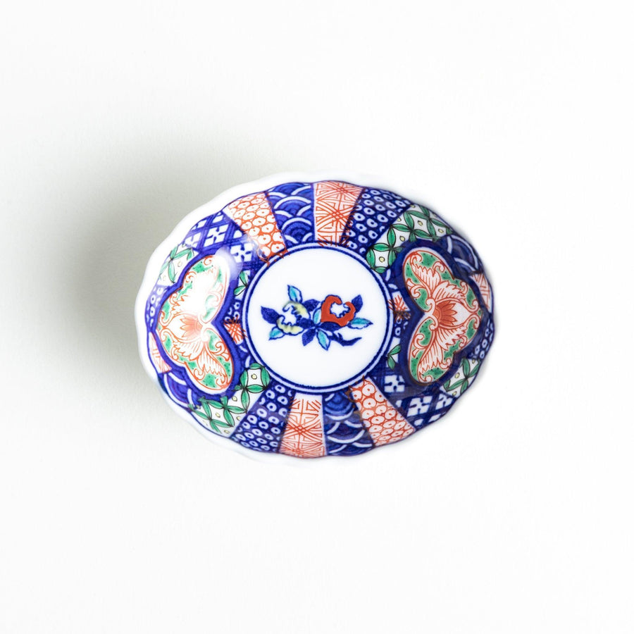 Small scalloped condiment bowl with floral motif and colorful geometric blue red and green patterns.