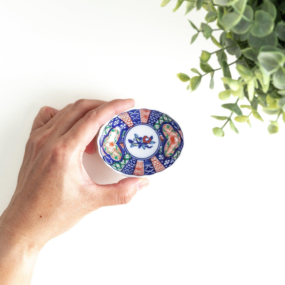 Small scalloped condiment bowl with floral motif and colorful geometric blue red and green patterns.