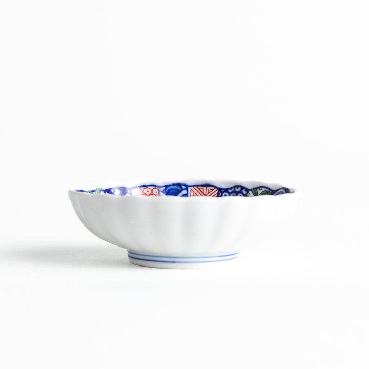 Small scalloped condiment bowl with floral motif and colorful geometric blue red and green patterns.