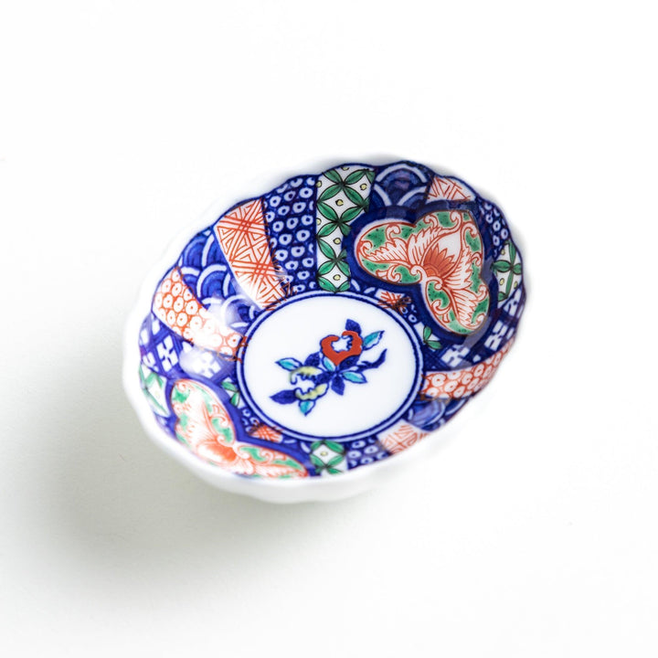Small scalloped condiment bowl with floral motif and colorful geometric blue red and green patterns.