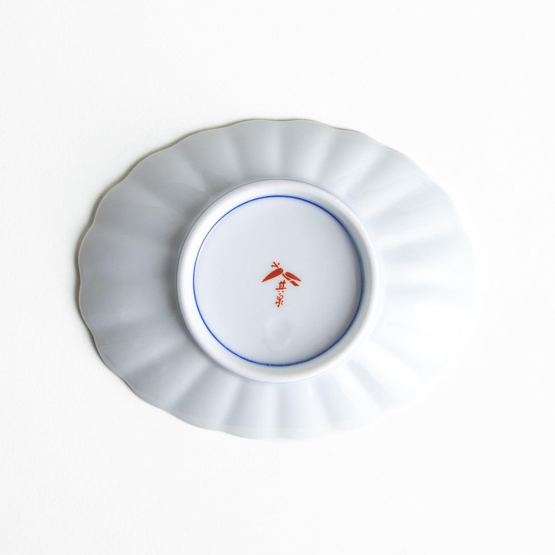 A sauce dish with a central floral motif and an intricate multicolored geometric pattern on the scalloped rim.