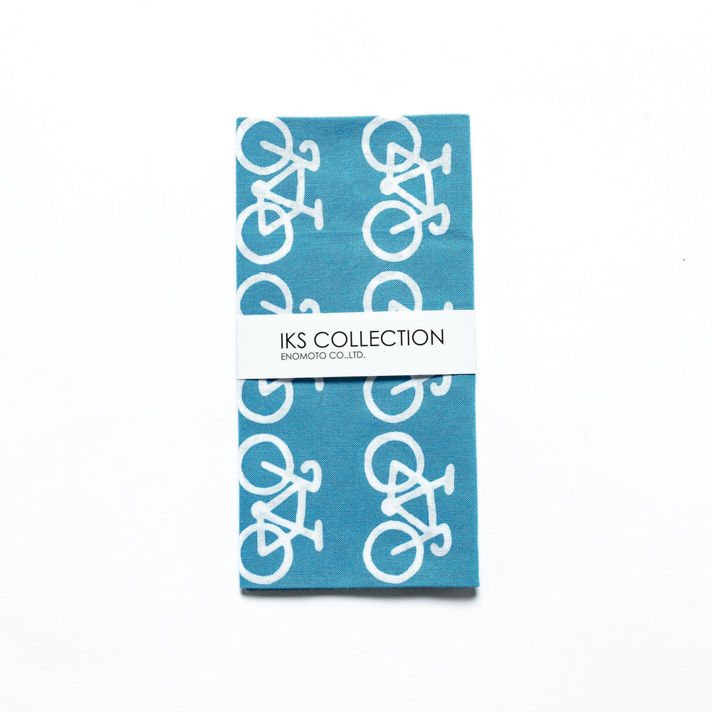 The blue tenugui is neatly folded, showcasing a product sleeve with the bicycle motif.