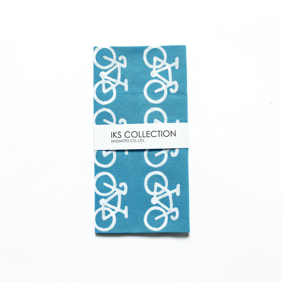 The blue tenugui is neatly folded, showcasing a product sleeve with the bicycle motif.