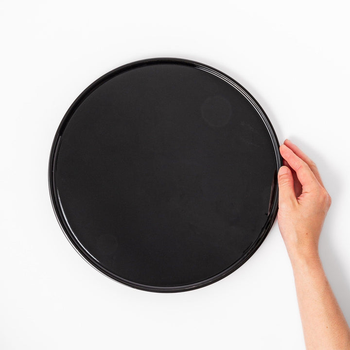 Glossy black Japanese wooden round tray with raised rim for serving tea or displaying tableware elegantly.
