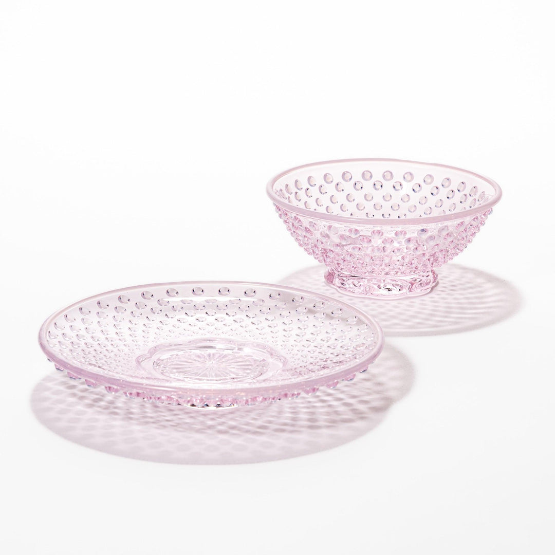 Pink glass dessert bowl and saucer with raised dot texture and starburst base, perfect for elegant sweets or fruit servings.