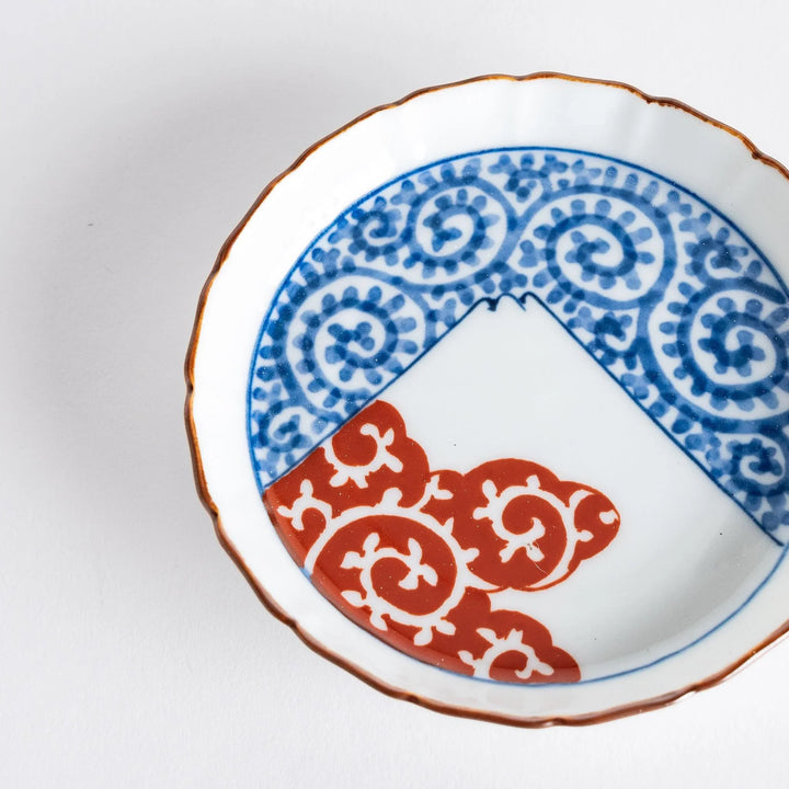 Raised rim Japanese sauce dish with blue spirals red clouds and Mount Fuji motif blending tradition and art.