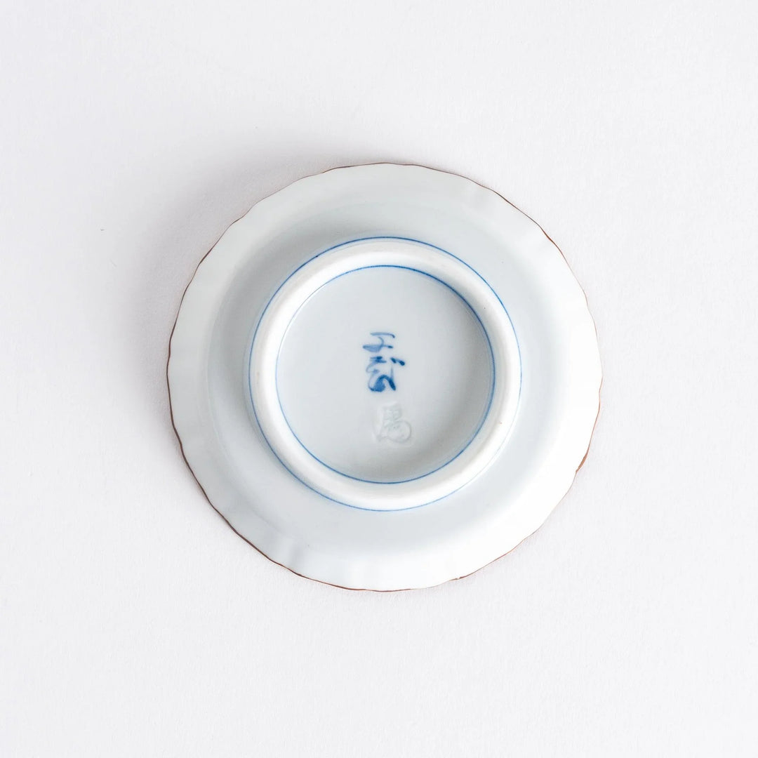 Raised rim Japanese sauce dish with blue spirals red clouds and Mount Fuji motif blending tradition and art.