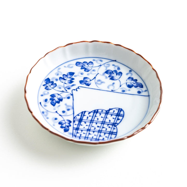 A ceramic dish with a blue and white design, showcasing a pattern of floral motifs and a depiction of Mount Fuji.