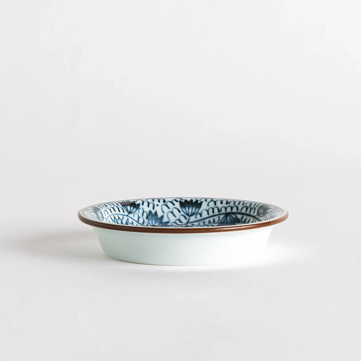 A small saucer adorned with detailed blue leaf patterns on a white background.