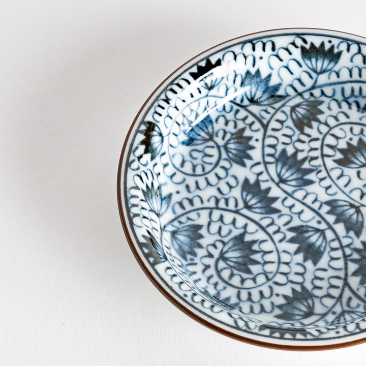 A small saucer adorned with detailed blue leaf patterns on a white background.