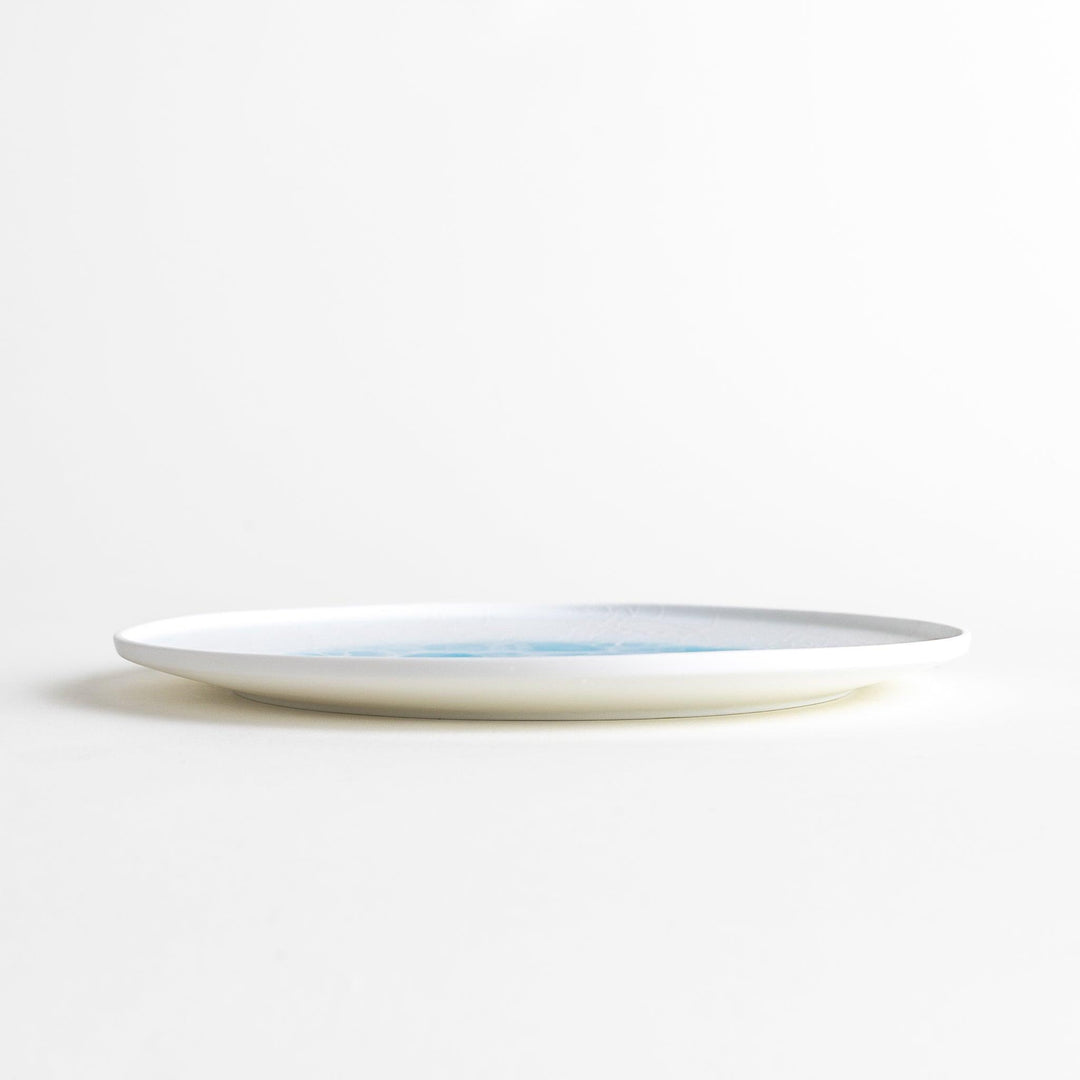 A white salad plate featuring a unique bubble design in shades of blue, resembling frothy ocean waves.