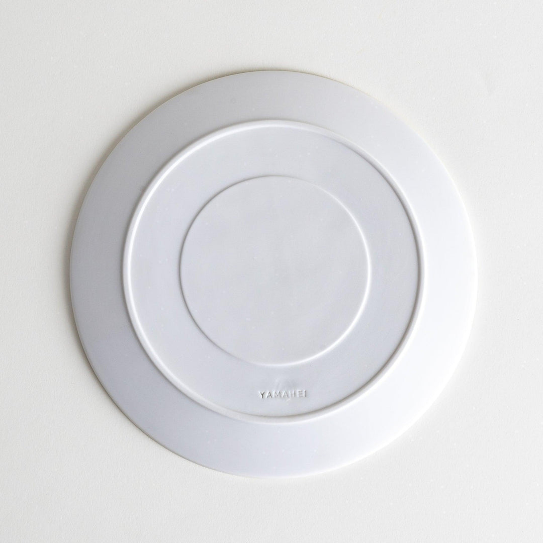 A white salad plate featuring a unique bubble design in shades of blue, resembling frothy ocean waves.