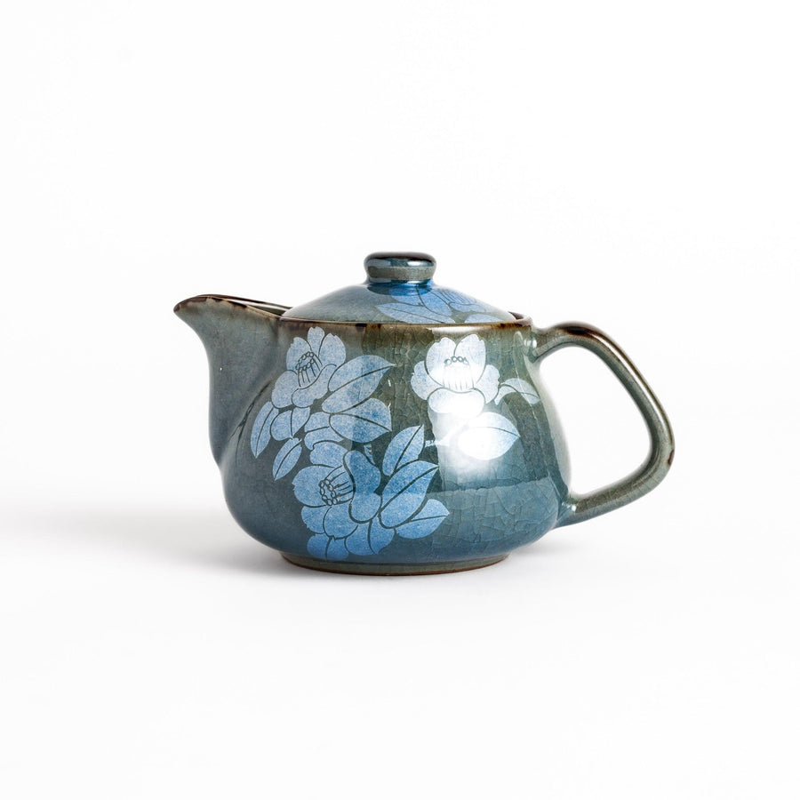 Stylish blue ceramic teapot with a delicate white camellia flower pattern. Perfect for enjoying your favorite tea.