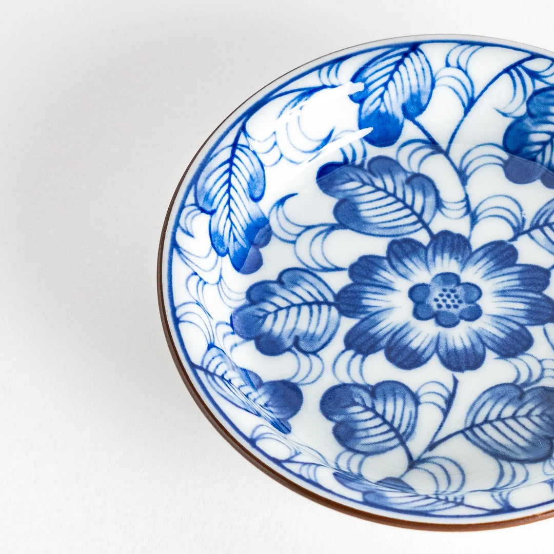 A round saucer featuring a delicate blue floral design on a white background.